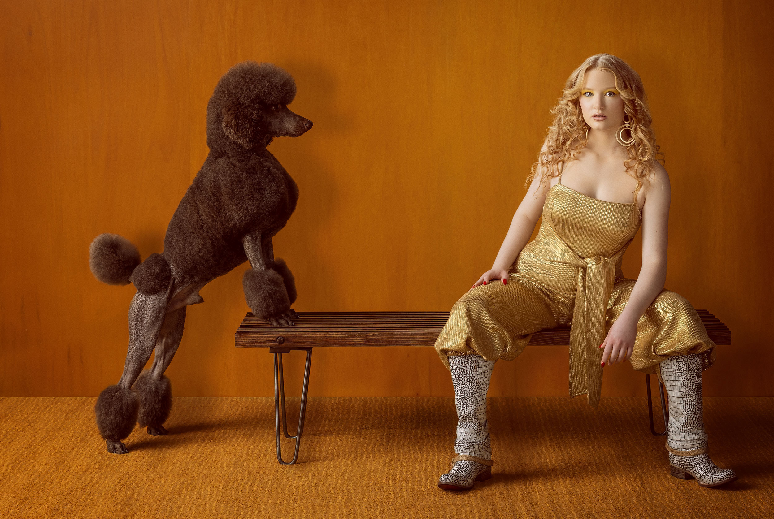 Female model sitting with a brown standard poodle. 