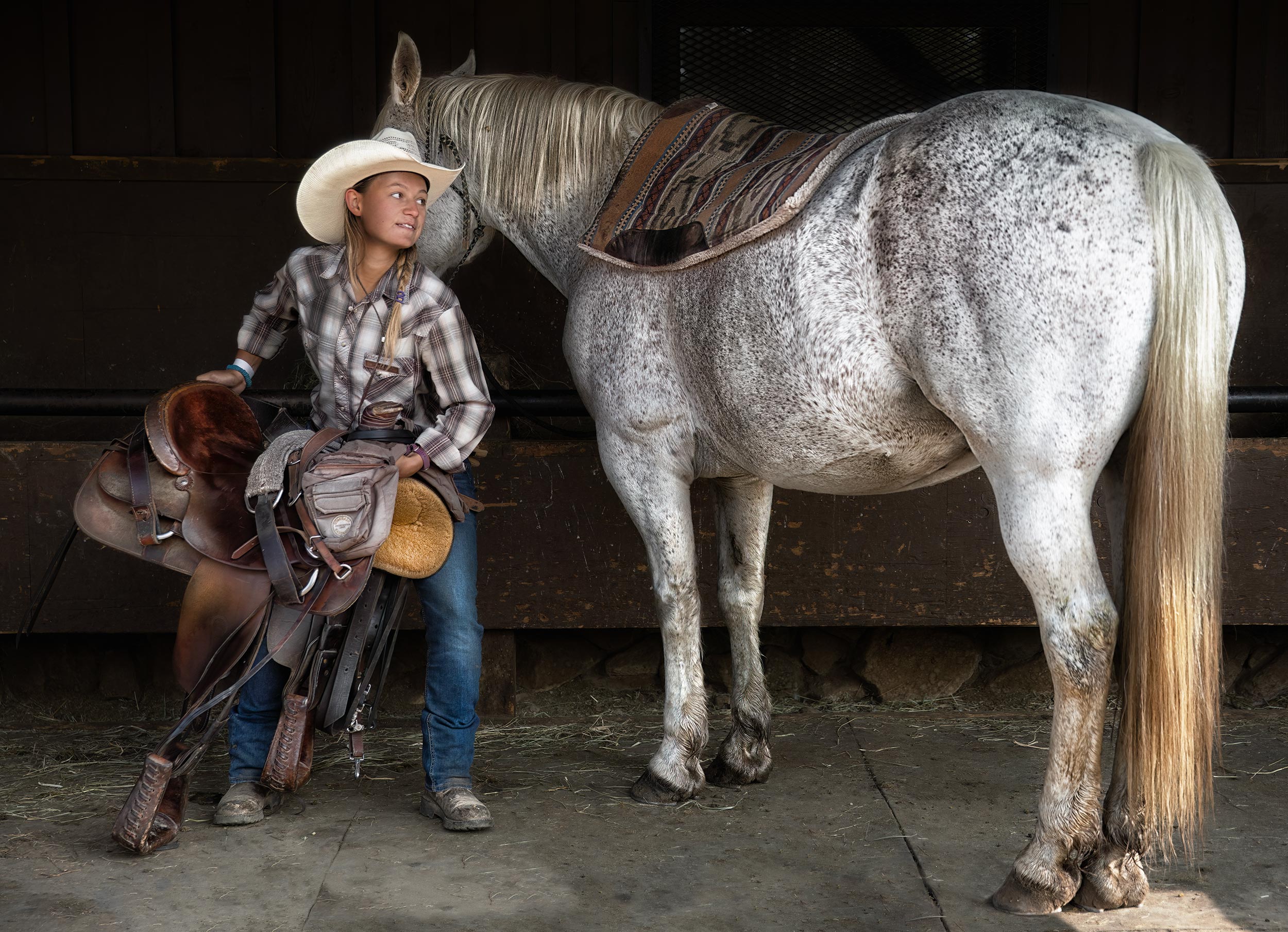 Cowgirl saddling horse for a ride. Livestock and agriculture photography