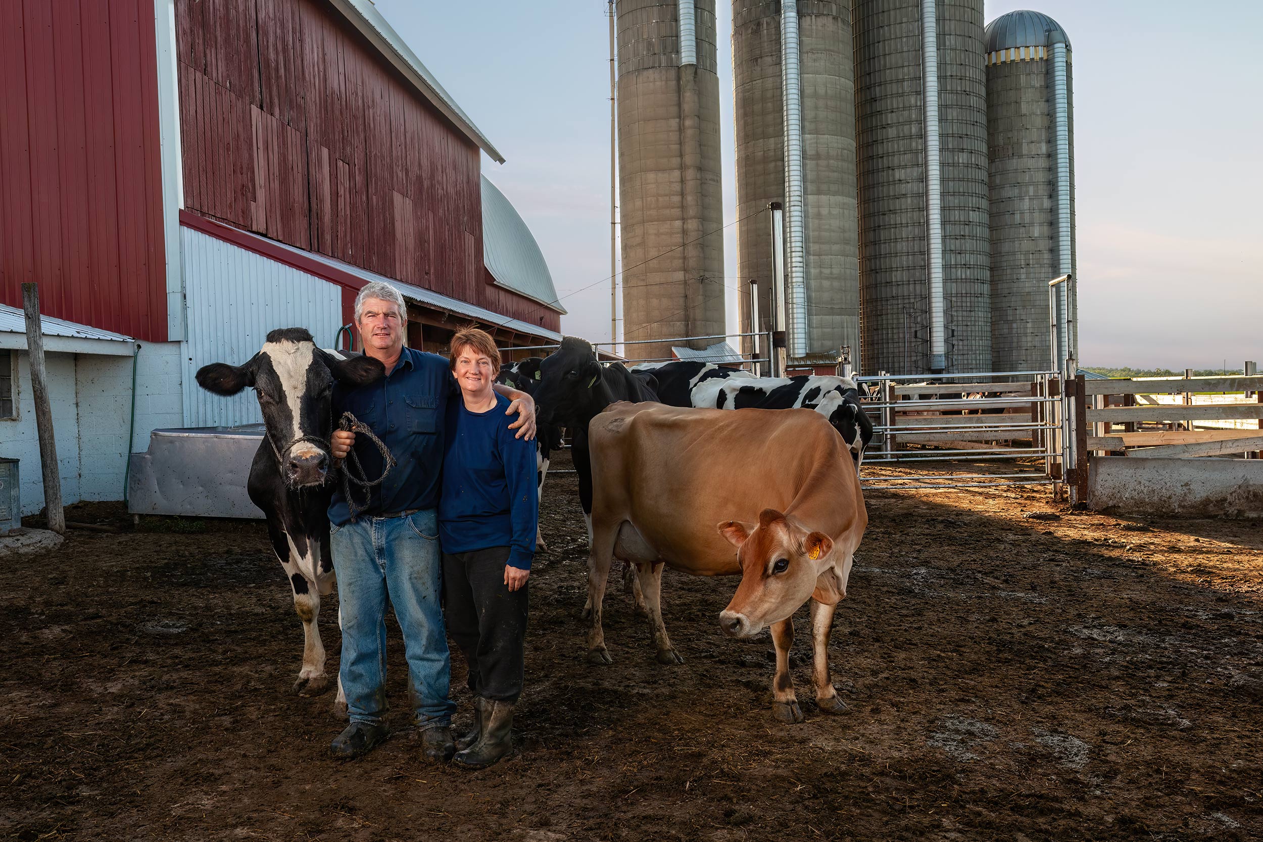 Dairy farmers posing with dairy cows in front of their milking barn and silos. Black and white image of cowgirls feeding grain before a ride in the round pen. Livestock and agriculture photography