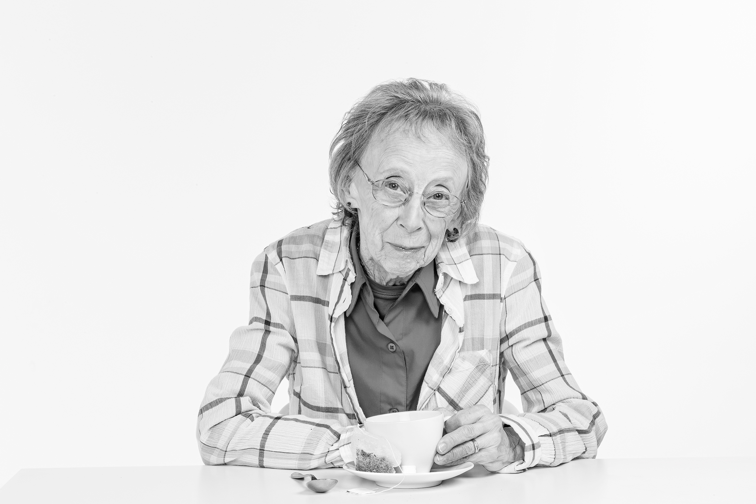 Black and white photo of a elderly woman drinking tea on white seamless
