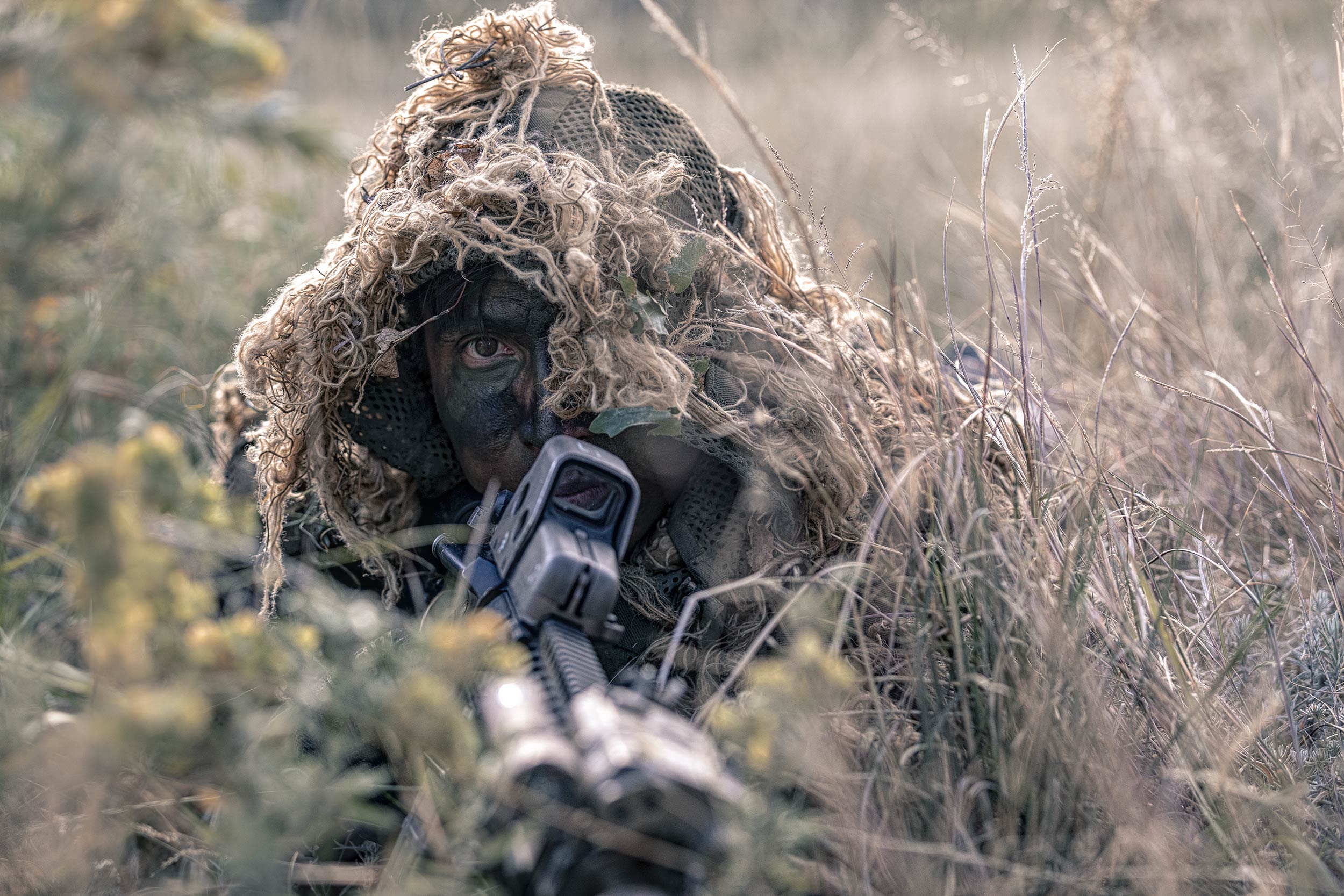 US Army Sniper on Ground camoflauged by surrounding grasses US Army Advertising