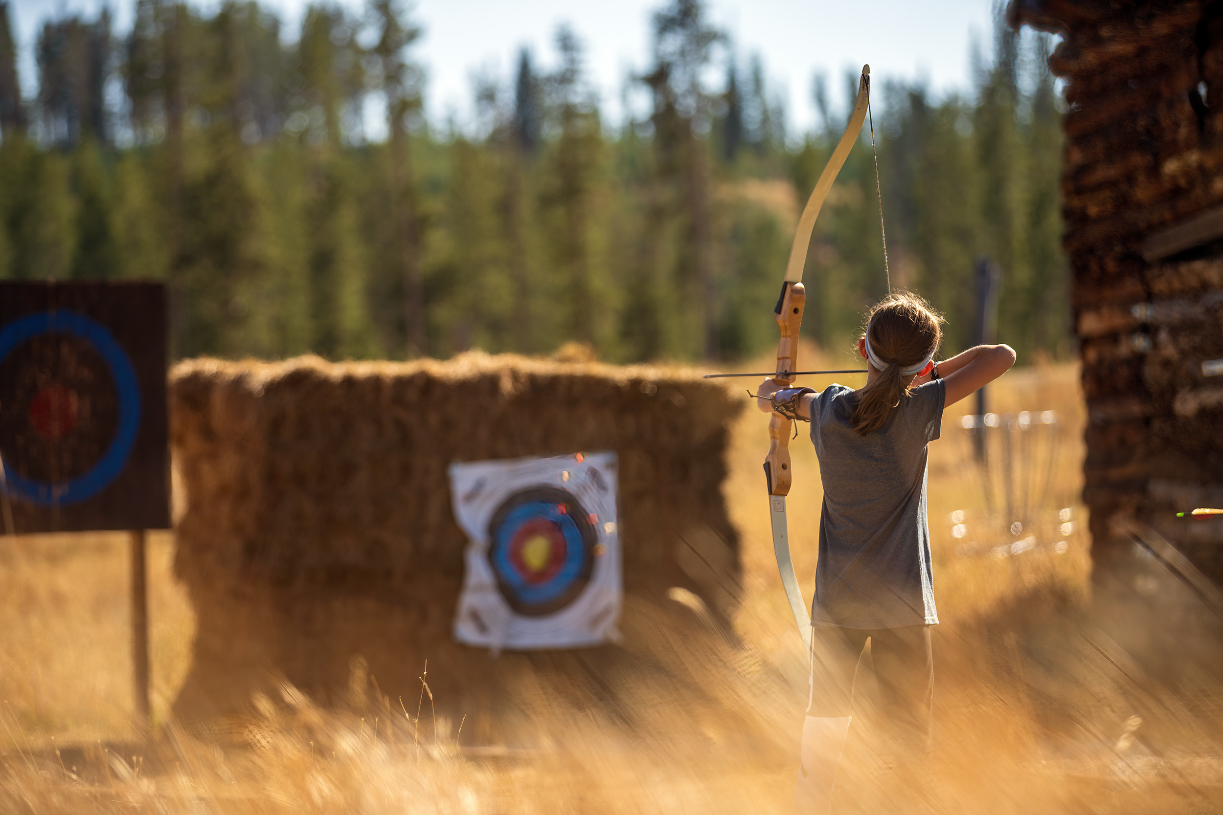A young girl practices archery for Devils Thumb Ranch
