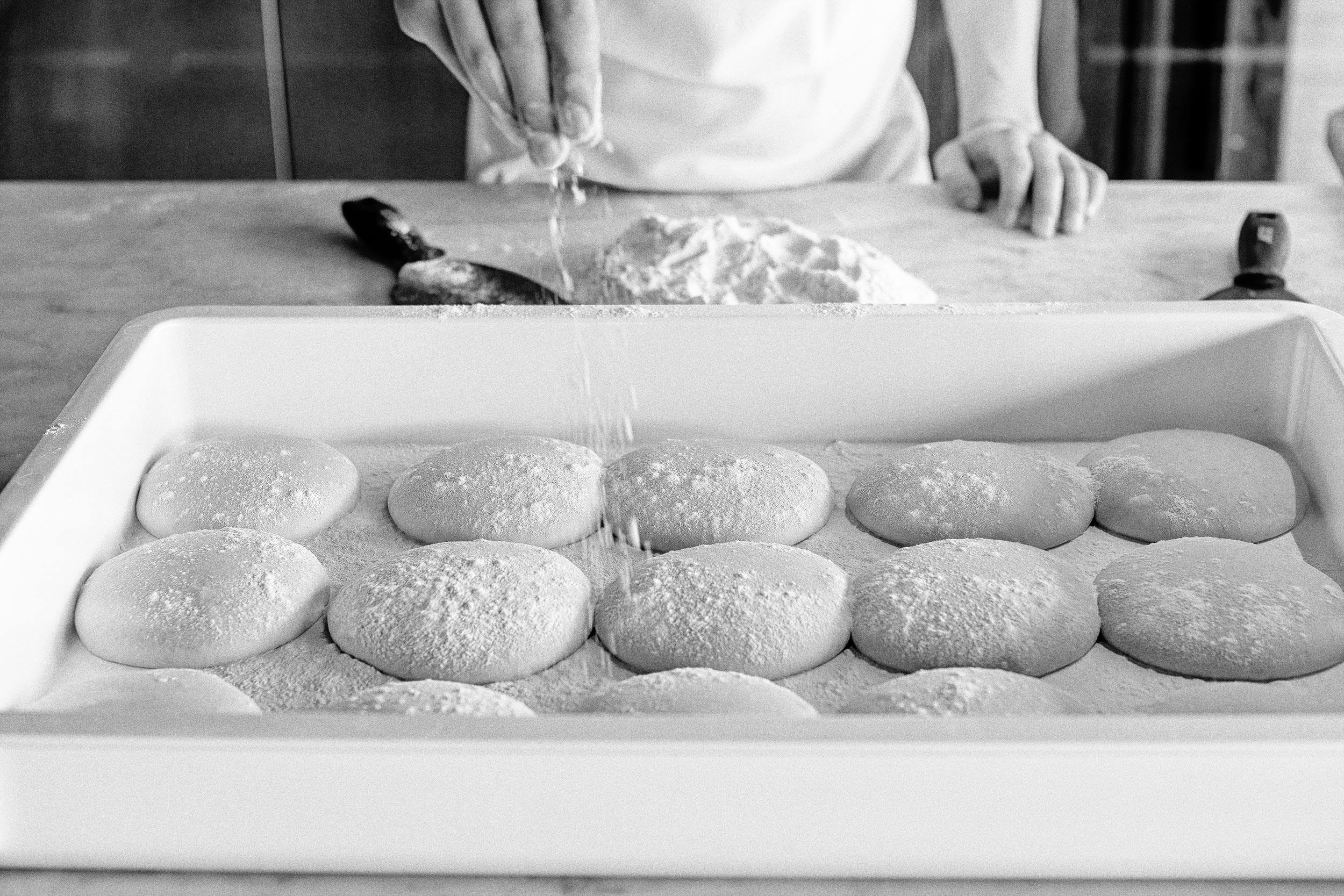 Pizza dough getting sprinkled with flour for Pizzaria Locale