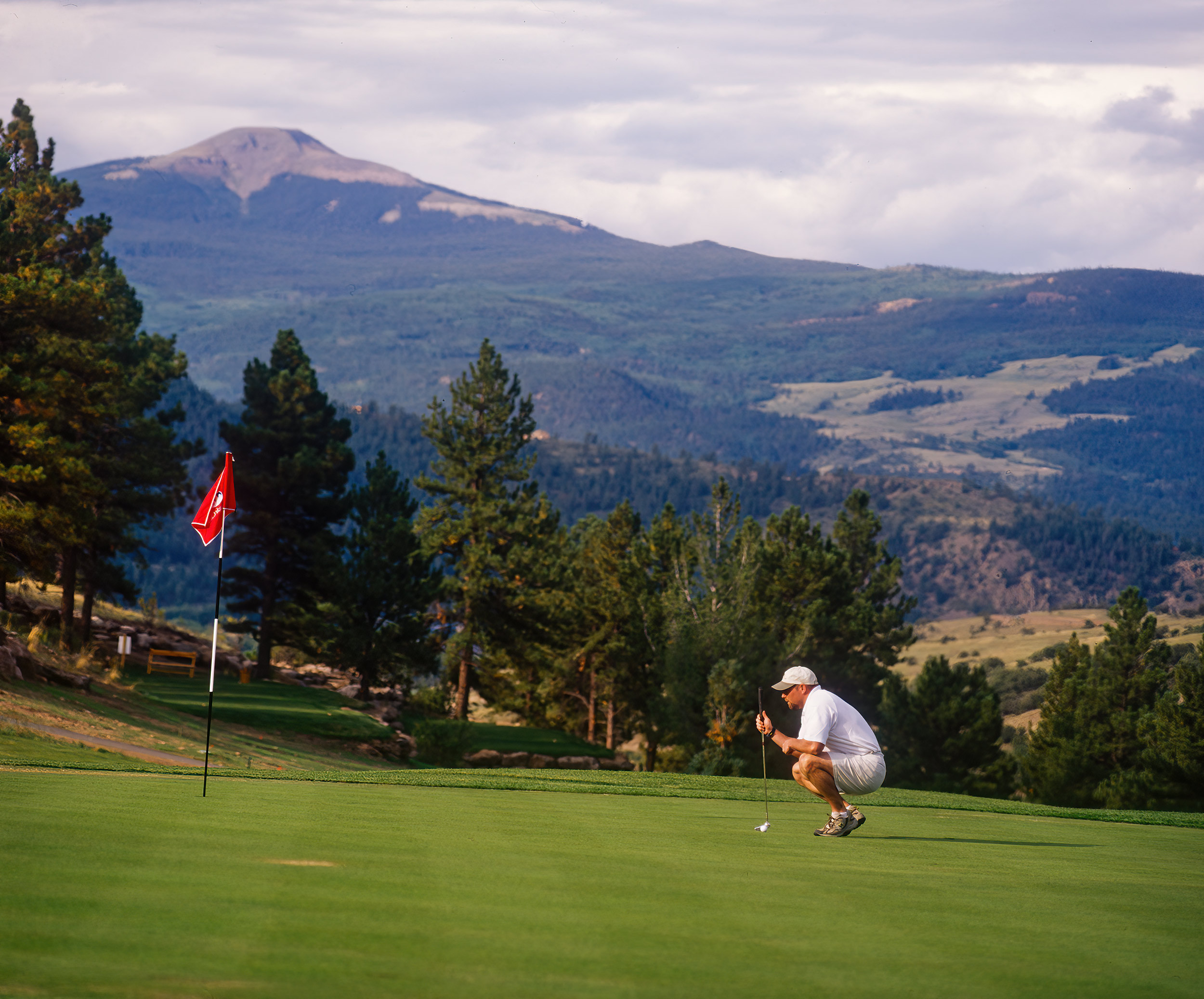 Golfer putting on golf course in mountains.
