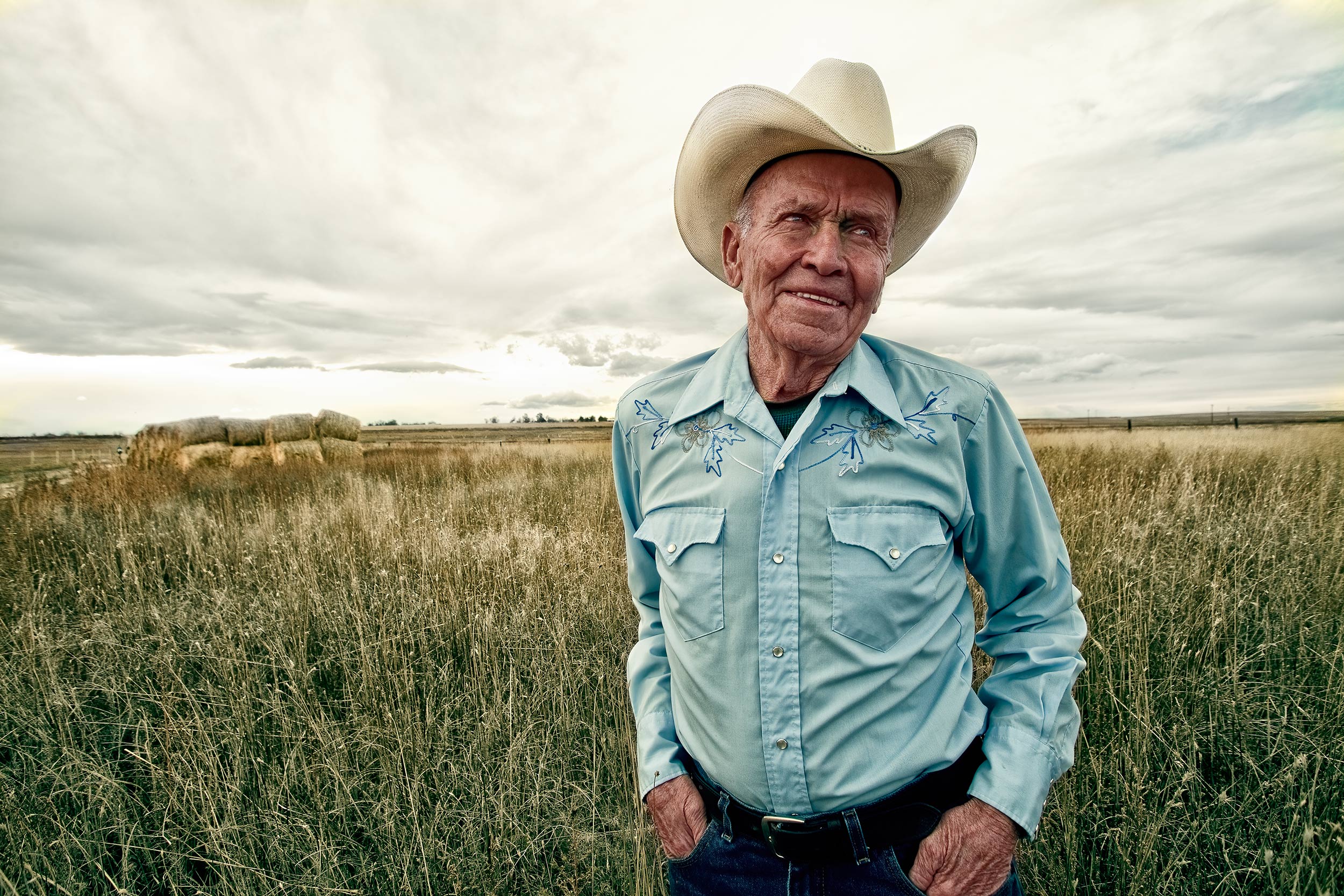 Portrait of a cowboy standing in a field. Livestock photography