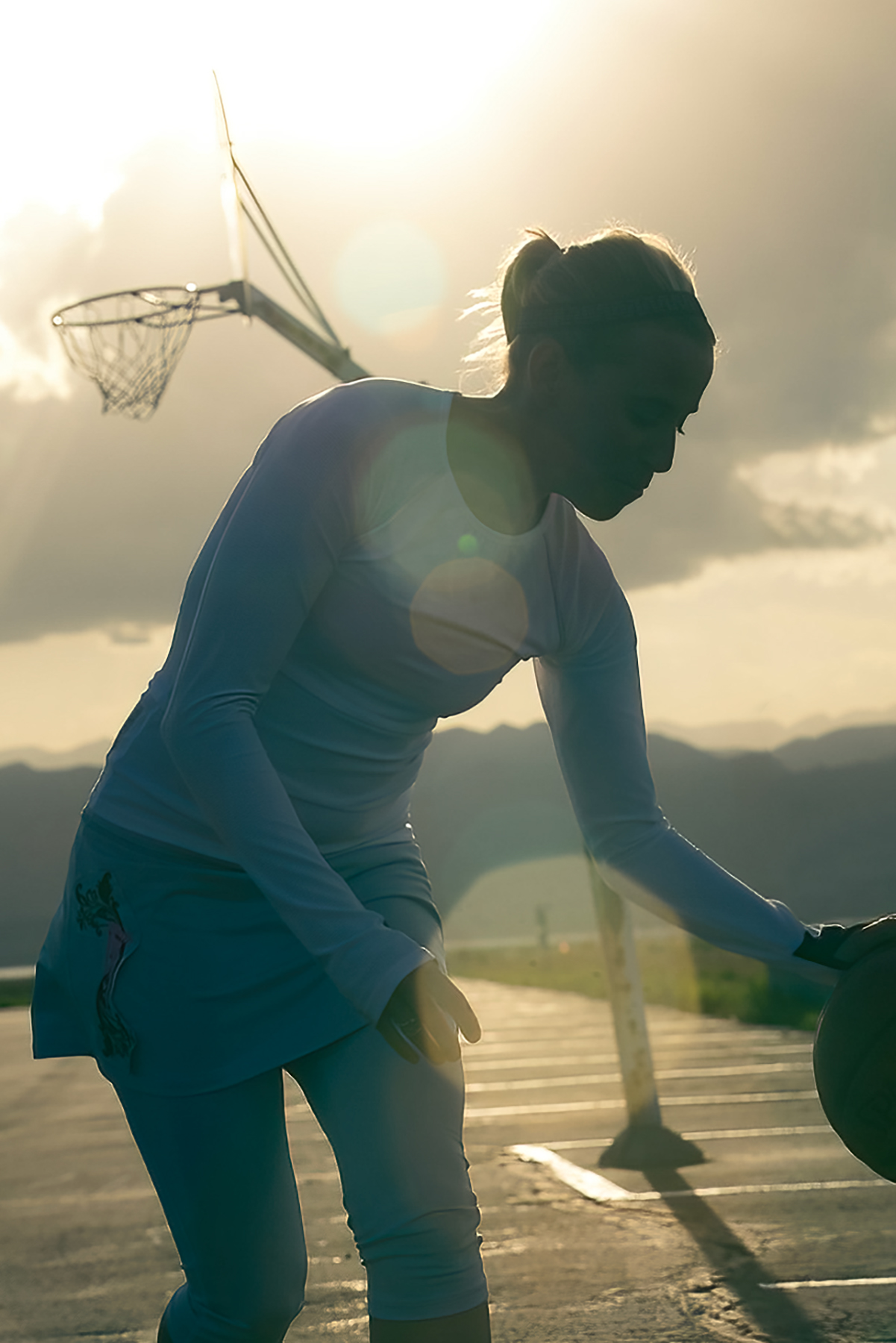 Woman shooting hoops in parking lot for Skirt Sports