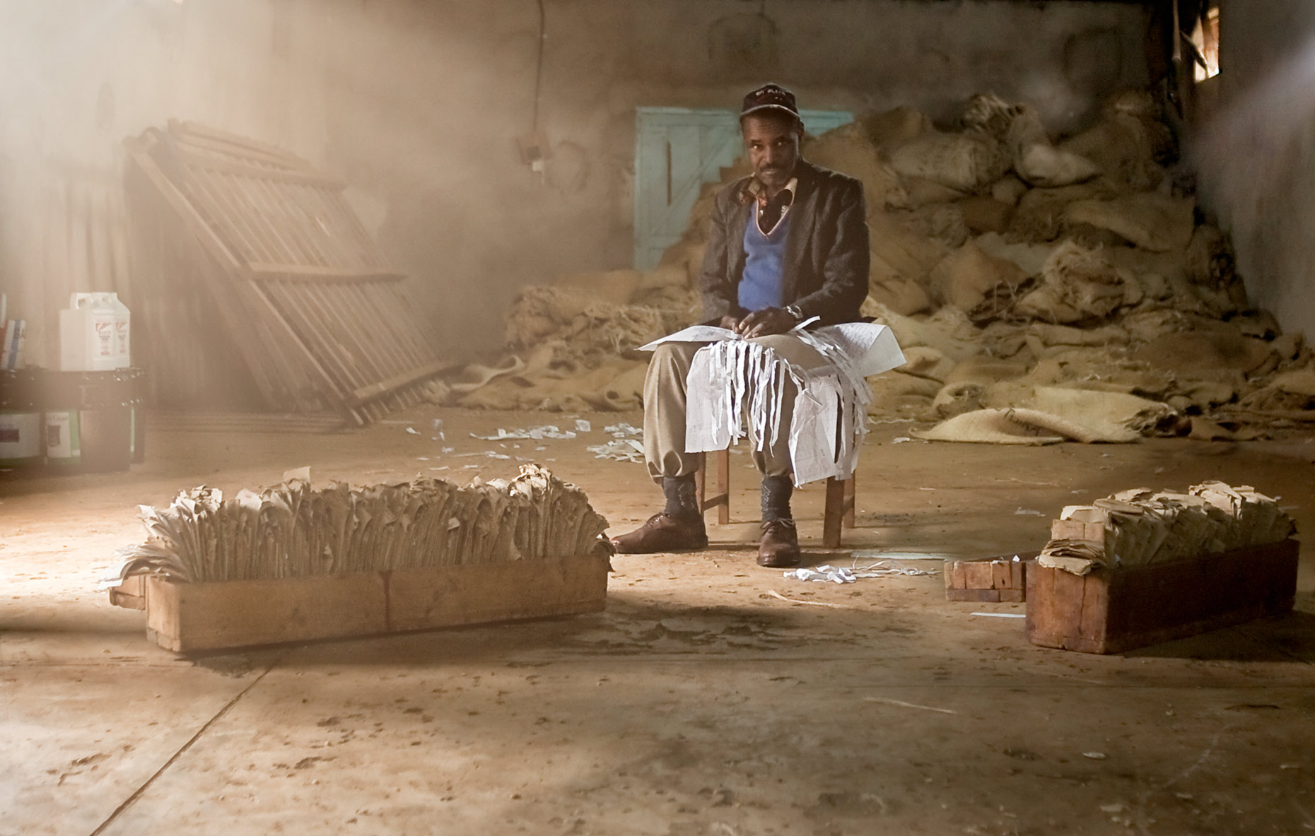 Coffee co-op worker sitting in warehouse with paperwork. Agriculture photography