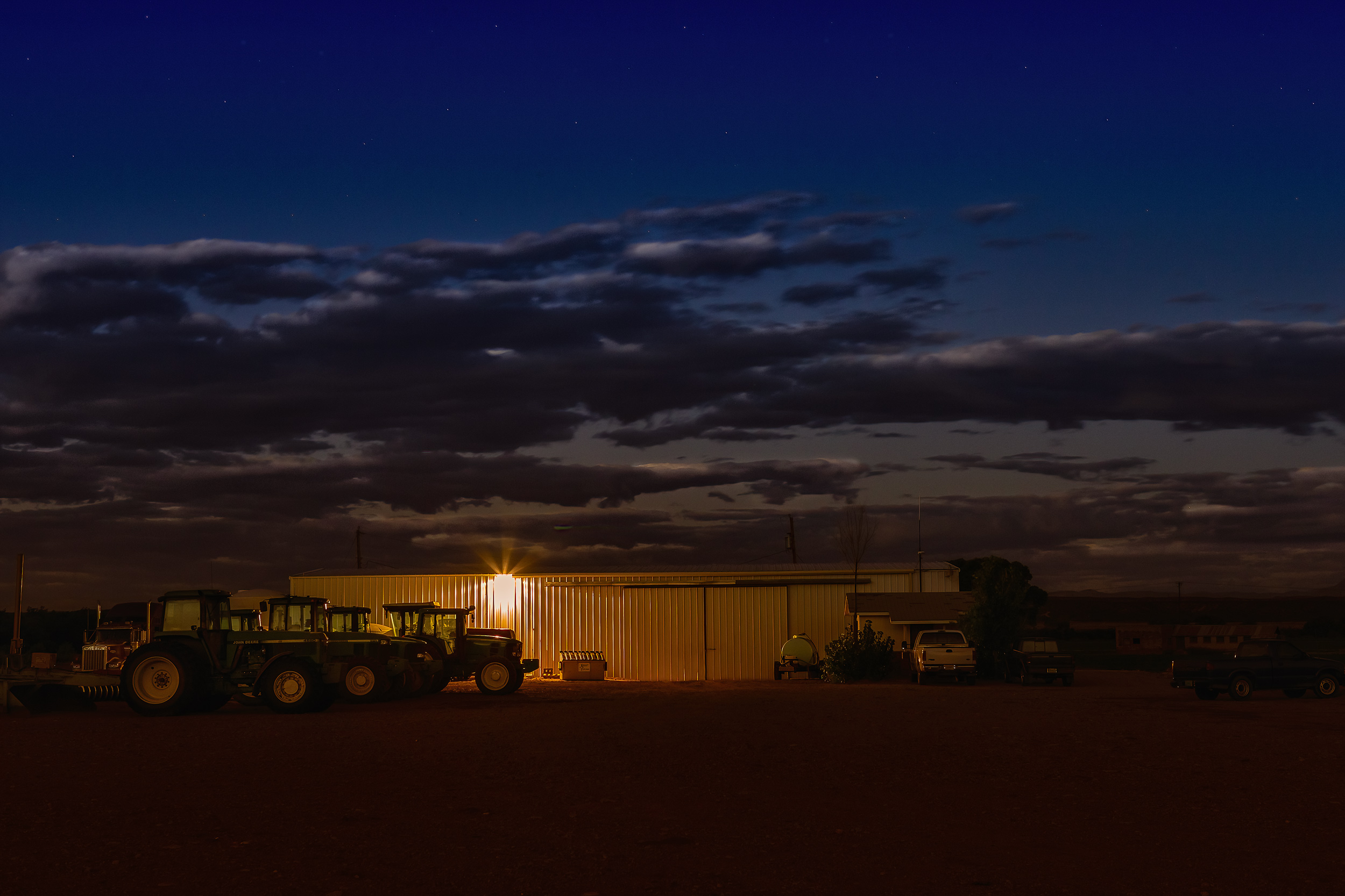 Tractors parked in front of a barn at night. Agriculture Photography