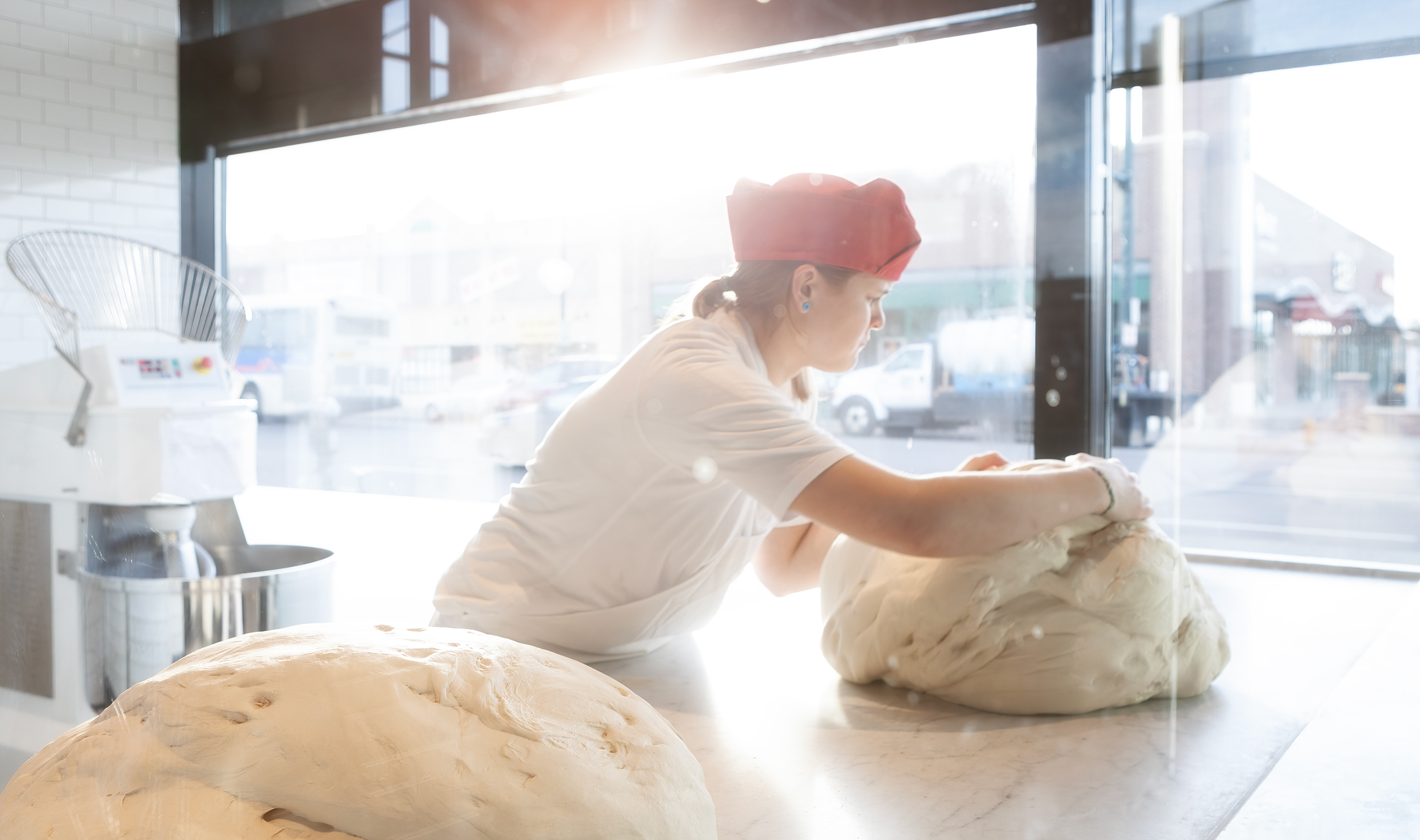Dough baker rolling pizza dough on slab for Pizzaria Locale